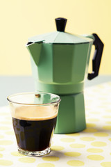 Glas of coffee and percolator on sunny background