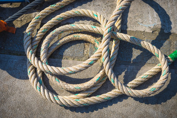 Marine rope tied knot lying on the sidewalk near the pier.