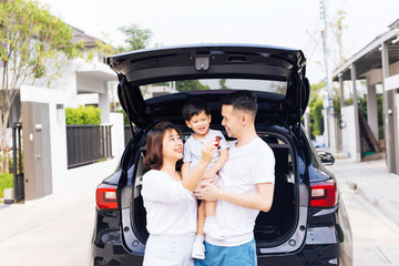 Happy Asian family standing on the back of SUV car with smile and happiness