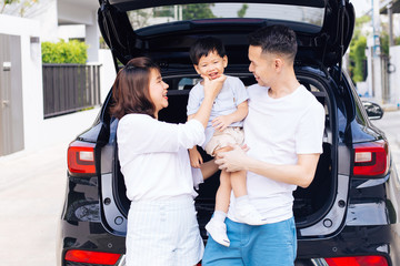 Happy Asian family standing on the back of SUV car with smile and happiness