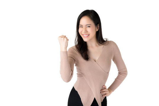 Cheerful young Asian woman raising her fists with delighted face, yes gesture