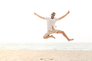 Fototapeta na wymiar Young energetic happy man jumping at the beach