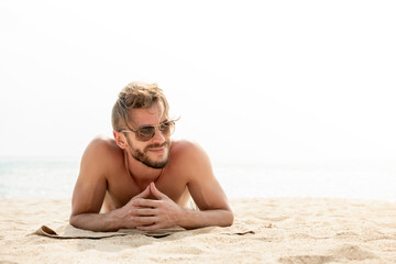 Young handsome man lying on stomach taking a sunbath at the beach on summer vacations