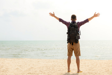 Happy tourist backpacker with open arms at the beach on summer holidays