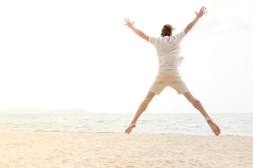 Young energetic happy tourist man jumping at the beach