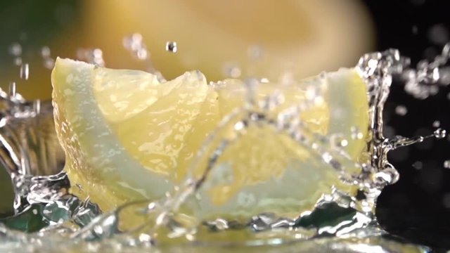 Close up Lemon slice hits on fresh water surface . Slow motion shot