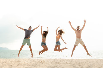 Happy energetic group of friends jumping at the beach during summer holidays