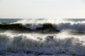 Sea waves breaking on the shore with sea foam