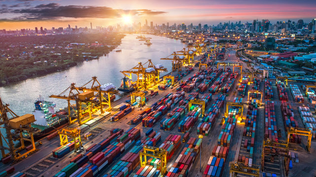 Logistics and transportation of Container Cargo ship and Cargo plane with working crane bridge in shipyard at sunrise, logistic import export and transport industry background