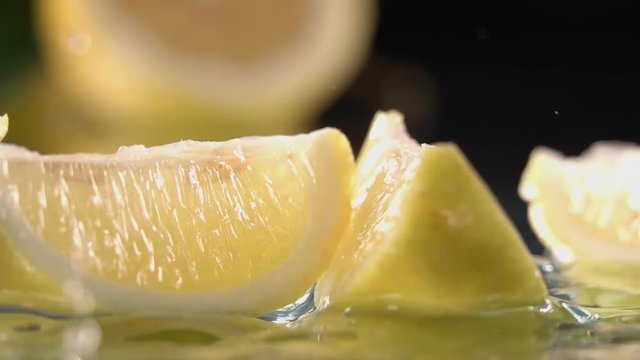 Lemon splits into halves on water. Slow motion shot