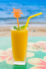 Mango shake with straw on the tropical beach