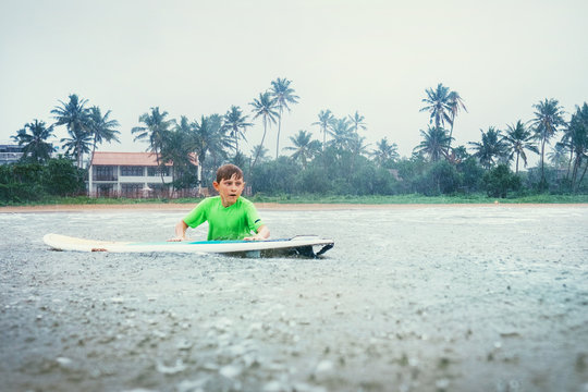 Boy learning to surf under the rain