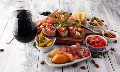 Italian antipasti wine snacks set. Cheese variety, Mediterranean olives, pickles, Prosciutto di Parma, tomatoes, artichokes and wine in glasses