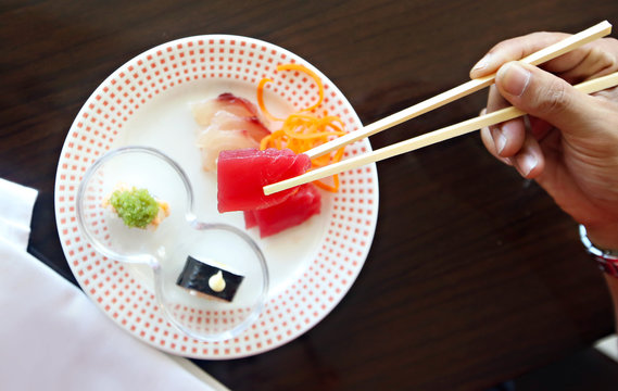 Men eat sushi with chopsticks