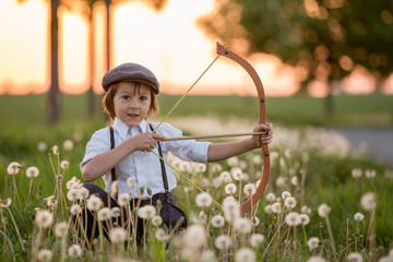 Portrait of child playing with bow and arrows, archery shoots a bow at the target.