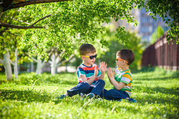Naklejka na ściany i meble Happy summer holidays. Two happy children on a green lawn at a summer park.