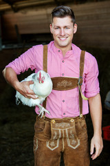 young bavarian man holding a white chicken