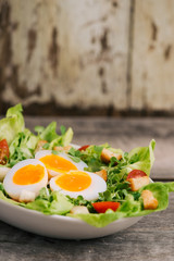 High Angle View of a Nutritious Vegetable Salad with Boiled Egg Slices, Served on a White Plate on Top of a Wooden Table