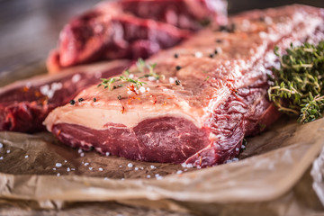 Raw rib eye beef steak with salt spices and herbs