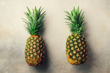 Two pineapples on gray background, top view, copy space. Minimal design. Vegan and vegetarian concept. Macro of pineapple fruit