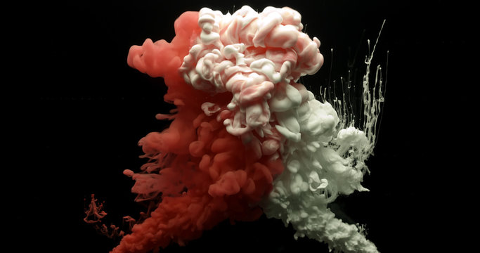 Red and white acrylic paint cloud spraying in water on black background.