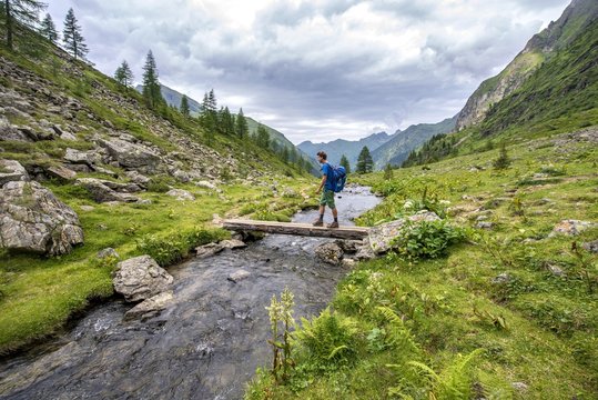 Hiker on a bridge over the Steinriesenbach, hiking trail to the Gollinghutte, Schladminger Hohenweg, Schladminger Tauern, Schladming, Styria, Austria, Europe