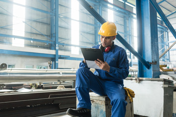 Determined Asian worker writing observations about the manufacturing process indoors