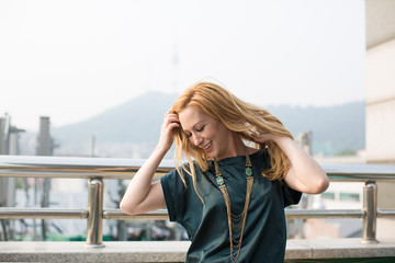 Carefree Woman Holding Hair and Smiling in City