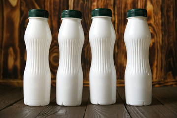 White plastic milk bottles on a wood background