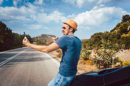 Tourist man making silly selfie photos in his vacation using phone