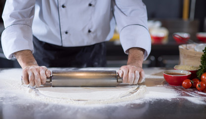 chef preparing dough for pizza with rolling pin