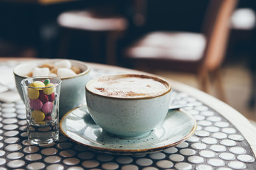 Close-up of cup of coffee on the table and candies in a modern cafe, selective focus