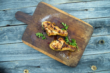 Grilled chicken legs with spices and herbs on wooden board