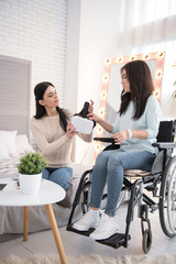 Innovative technology. Musing friend and crippled woman holding VR headset and looking down