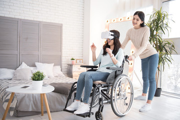Virtual universe. Gay friend standing while immobile woman wearing VR glasses