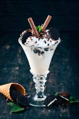 Ice cream with chocolate cookies. On a black wooden background. Copy space.