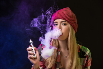 Obraz premium Vaping girl. Young hipster woman vape e-cig on studio on black background. Hip-hop style. Close up.