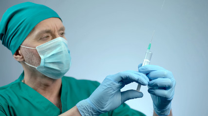 Male physician checking syringe for injection, vaccination in epidemic season