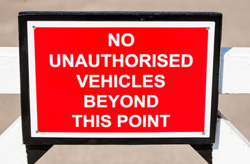 NO UNAUTHORISED VEHICLES BEYOND THIS POINT sign attached to a white gate.
