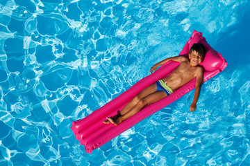 Boy sunbathing on inflatable lounge in the pool