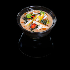 Asian soup with eel. In a plate on a black background with reflection