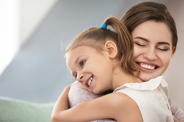 Portrait of happy mother and daughter hugging at home