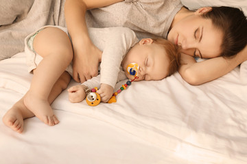 Mother with her baby sleeping on bed at home