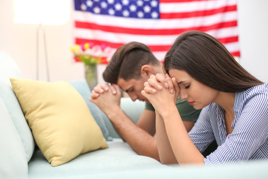 Young couple praying for America at home