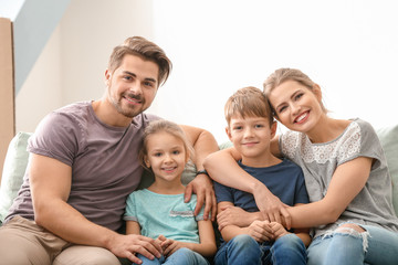 Portrait of couple with children on sofa at home. Happy family