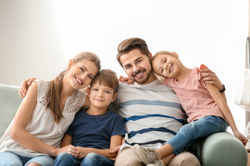 Portrait of couple with children on sofa at home. Happy family