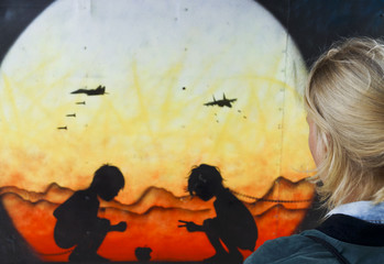 Woman looking at graffity art of playing children in danger