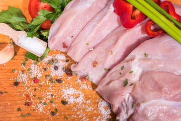 Fresh raw veal meat with spice and vegetables on wooden background