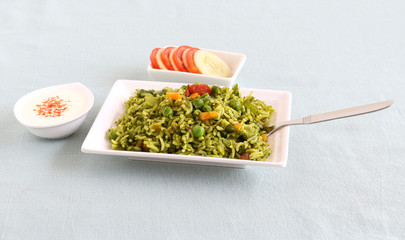Palak rice, biryani or pilaf, which is made from spinach and vegetables is an Indian vegetarian healthy food, with yogurt and tomato-cucumber salad.