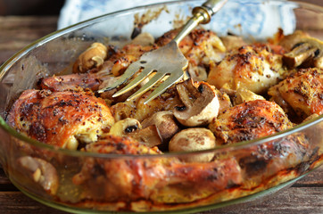 Chicken legs in mustard with mushrooms in glass on wooden background